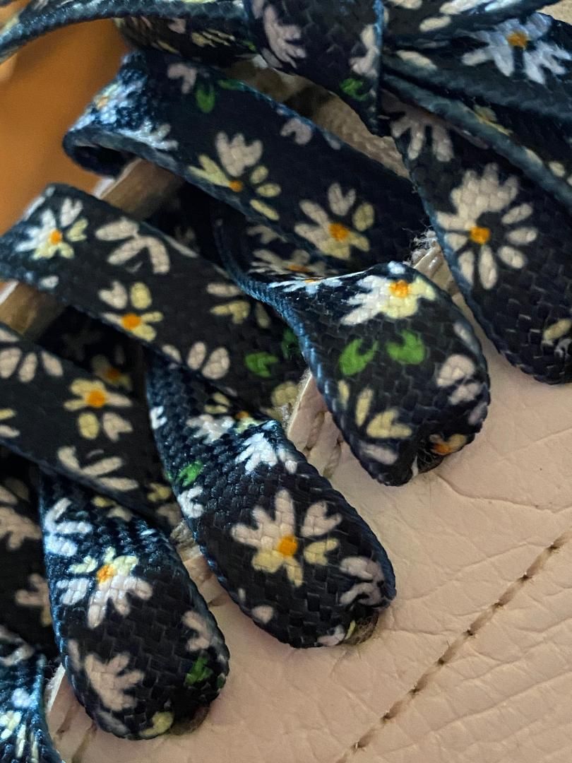 New - White daisy flat laces on black background