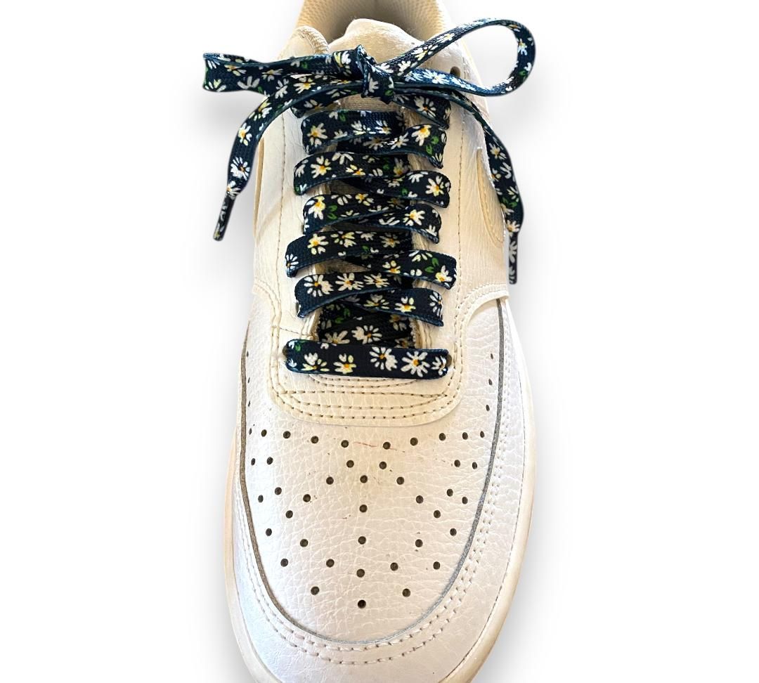 New - White daisy flat laces on black background